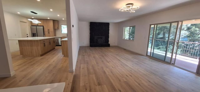 interior space featuring light hardwood / wood-style floors, hanging light fixtures, and appliances with stainless steel finishes