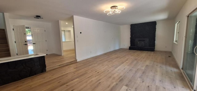 unfurnished living room with light hardwood / wood-style flooring and a stone fireplace