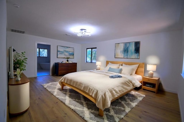 bedroom featuring dark wood-type flooring and ensuite bathroom