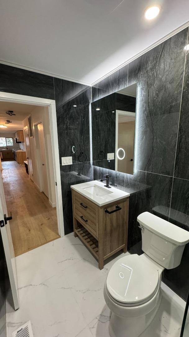 bathroom featuring tile walls, toilet, and vanity