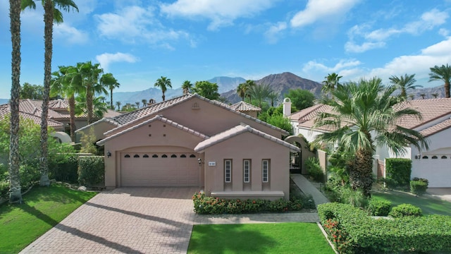 mediterranean / spanish house with a mountain view, a front lawn, and a garage