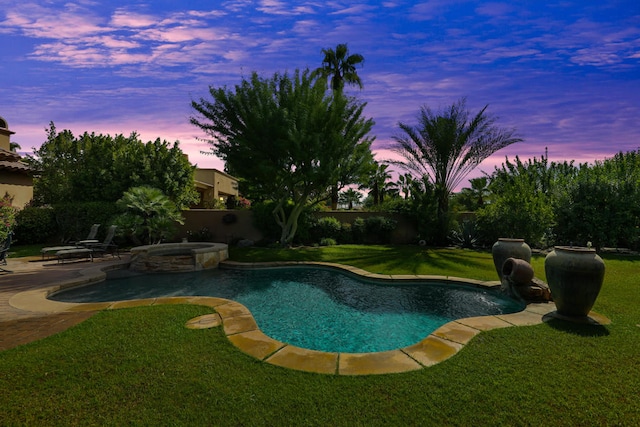 pool at dusk with a lawn and an in ground hot tub