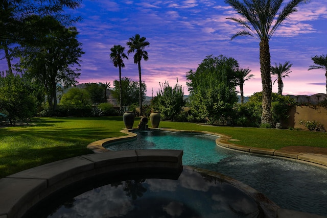 pool at dusk with a lawn and an in ground hot tub