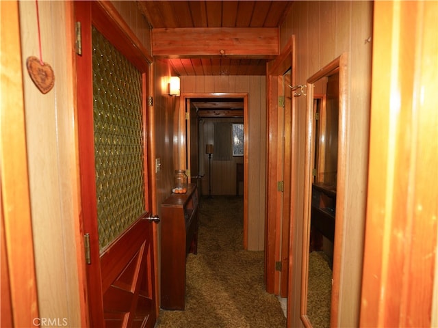 corridor featuring wooden walls, dark colored carpet, and wooden ceiling