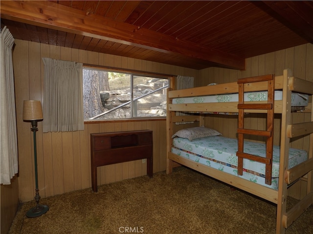 unfurnished bedroom featuring wooden walls, wood ceiling, beam ceiling, and carpet