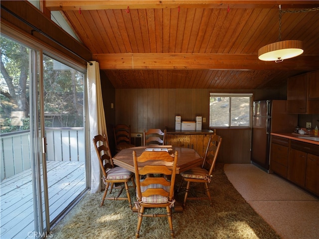 dining room featuring wooden ceiling, vaulted ceiling with beams, wood walls, and sink