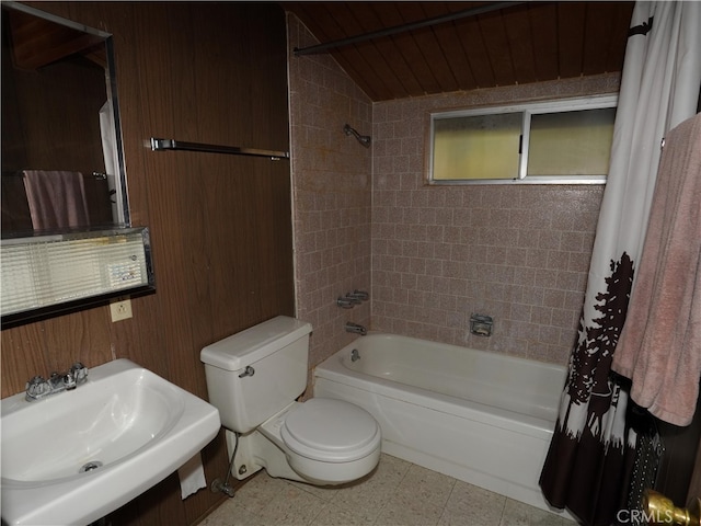 full bathroom featuring shower / bath combo, sink, wood walls, vaulted ceiling, and toilet