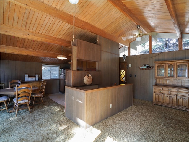 kitchen with lofted ceiling with beams, wooden walls, plenty of natural light, and carpet flooring