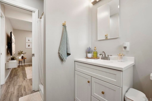 bathroom with hardwood / wood-style floors, a shower with curtain, vanity, and toilet