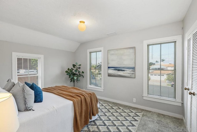 bedroom with vaulted ceiling, multiple windows, and carpet flooring