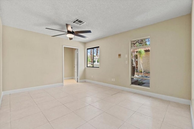 tiled empty room with ceiling fan and a textured ceiling