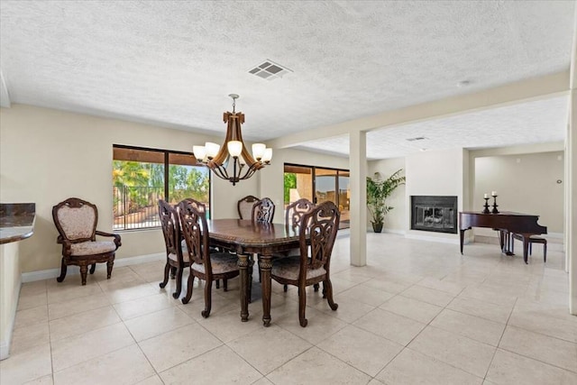 dining space with light tile patterned floors, a textured ceiling, and a notable chandelier