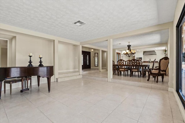 interior space with a chandelier, light tile patterned floors, and a textured ceiling