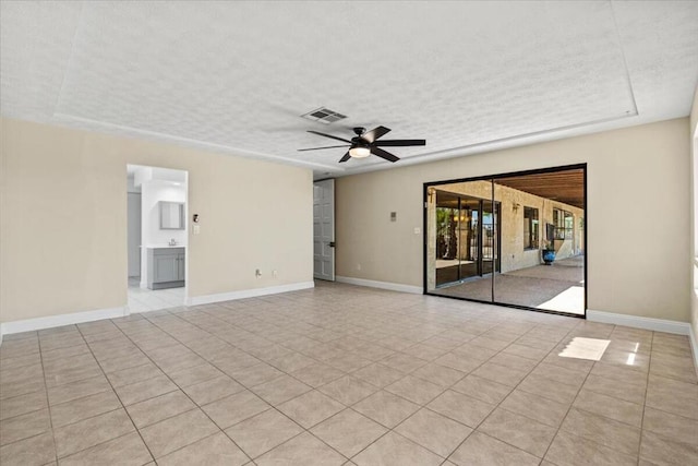 spare room with ceiling fan, light tile patterned flooring, and a textured ceiling