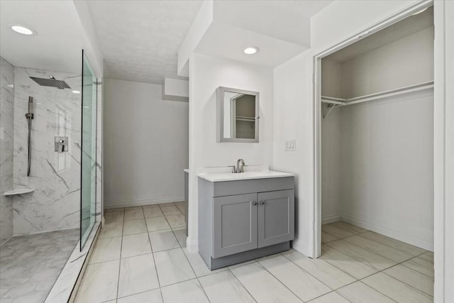 bathroom with a tile shower, vanity, and tile patterned floors