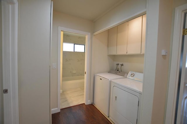 washroom featuring washer and clothes dryer, dark wood-type flooring, and cabinets