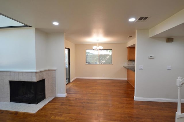 interior space featuring a tile fireplace, dark wood-type flooring, and an inviting chandelier