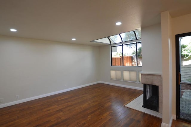 unfurnished living room with dark hardwood / wood-style floors and a tiled fireplace