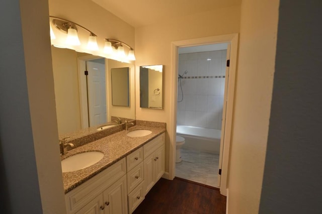 full bathroom featuring hardwood / wood-style floors, vanity, toilet, and tiled shower / bath