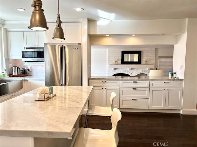 kitchen featuring light stone counters, white cabinets, stainless steel appliances, and tasteful backsplash