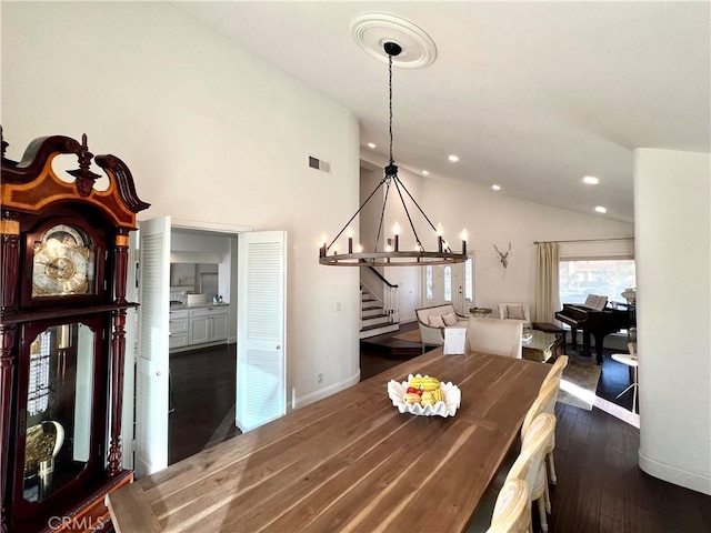 dining area with dark wood-type flooring, a chandelier, and vaulted ceiling