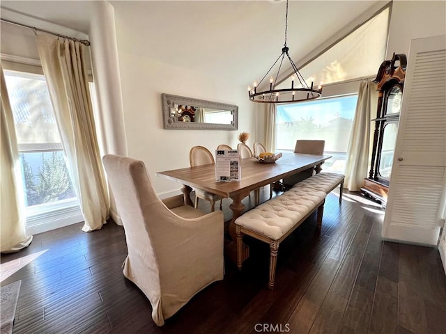 dining space with dark hardwood / wood-style floors, lofted ceiling, and an inviting chandelier