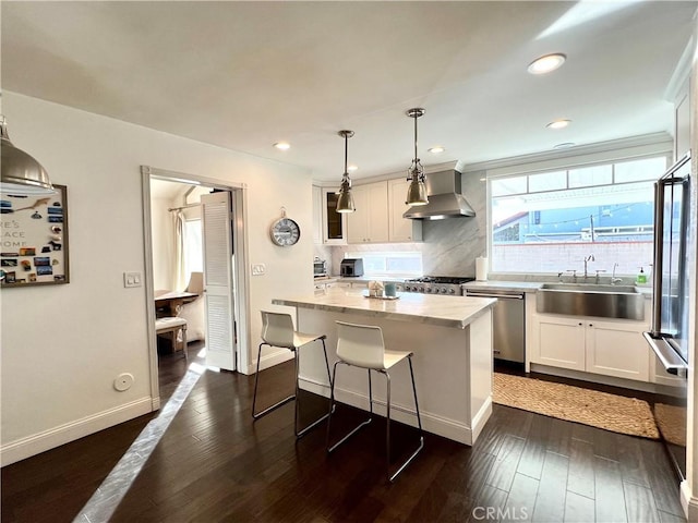 kitchen with a center island, white cabinetry, stainless steel appliances, sink, and hanging light fixtures