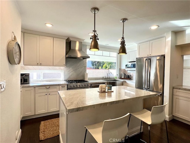 kitchen with wall chimney range hood, a center island, sink, light stone countertops, and high quality appliances