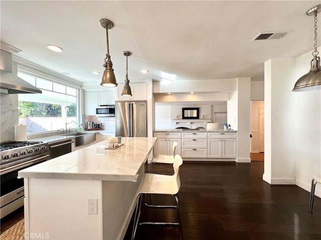 kitchen featuring decorative backsplash, high end appliances, pendant lighting, light stone counters, and a center island