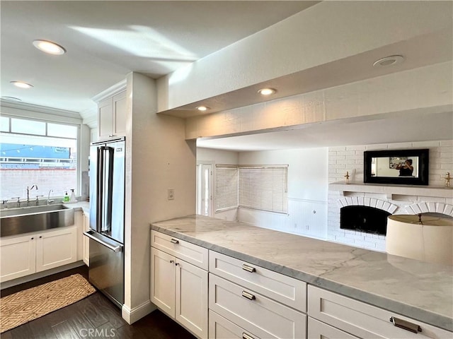 kitchen featuring light stone countertops, sink, white cabinets, and high end fridge