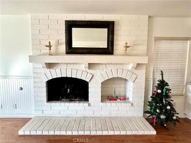 room details featuring a brick fireplace and wood-type flooring