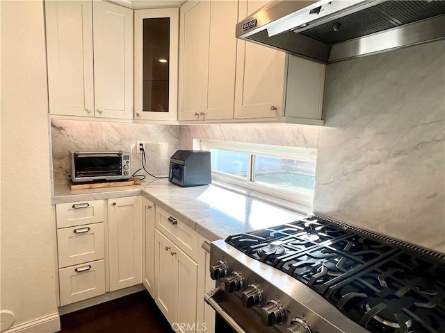 kitchen featuring exhaust hood, white cabinetry, high end stainless steel range, and light stone counters