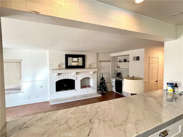 unfurnished living room with wine cooler, built in shelves, and a brick fireplace