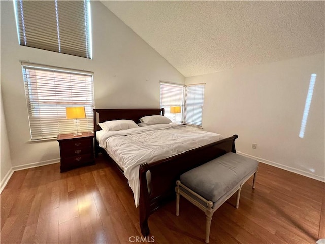 bedroom with wood-type flooring, multiple windows, a textured ceiling, and high vaulted ceiling