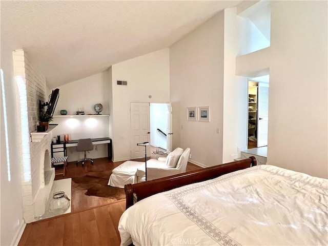 bedroom featuring built in desk, wood-type flooring, and high vaulted ceiling