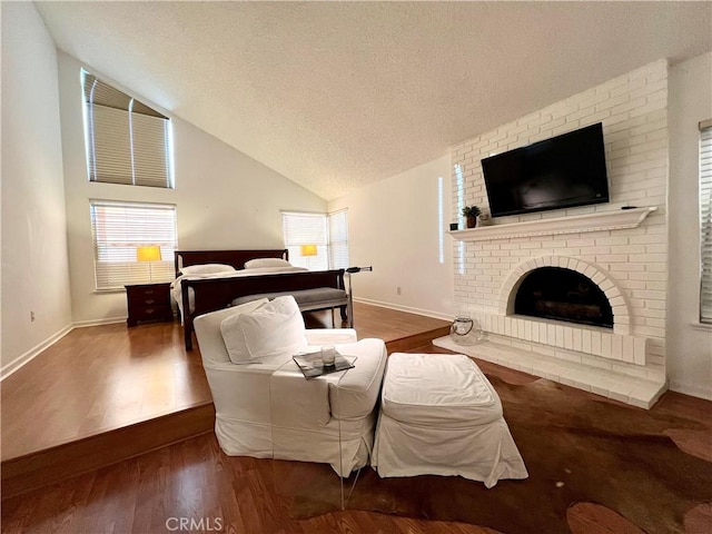 bedroom with lofted ceiling, dark hardwood / wood-style flooring, a textured ceiling, and a brick fireplace