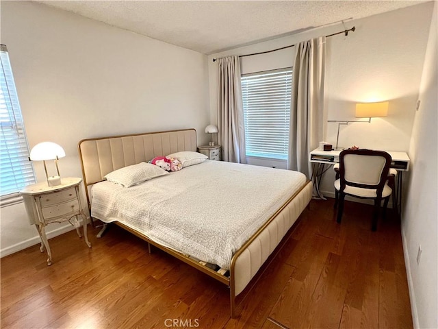 bedroom with a textured ceiling and dark hardwood / wood-style flooring