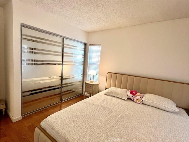 bedroom with a textured ceiling and dark hardwood / wood-style flooring