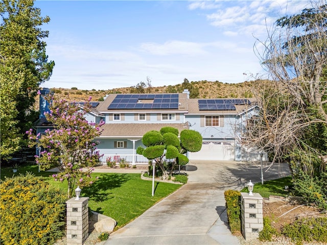 view of front of property featuring a garage, a porch, a front yard, and solar panels