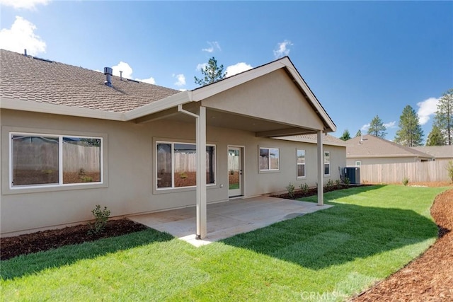 back of house featuring cooling unit, a patio area, and a yard