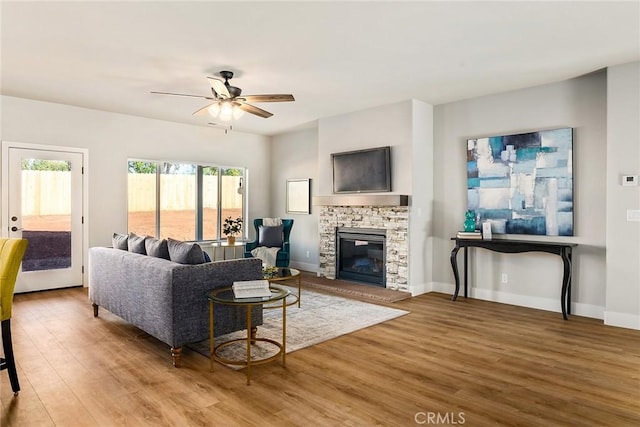 living room featuring hardwood / wood-style floors, ceiling fan, and a fireplace