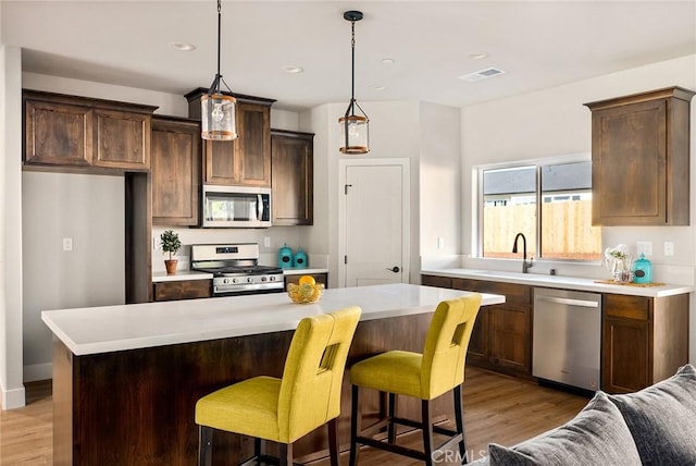 kitchen featuring pendant lighting, a center island, light hardwood / wood-style flooring, and appliances with stainless steel finishes