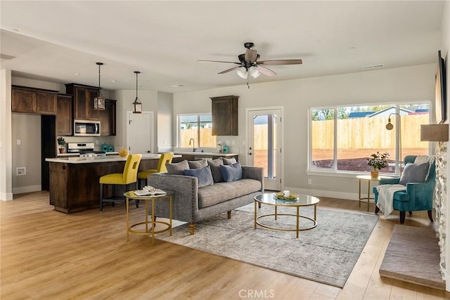 living room featuring plenty of natural light, ceiling fan, sink, and light hardwood / wood-style flooring