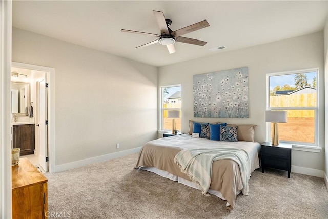 bedroom with ensuite bath, ceiling fan, and light colored carpet