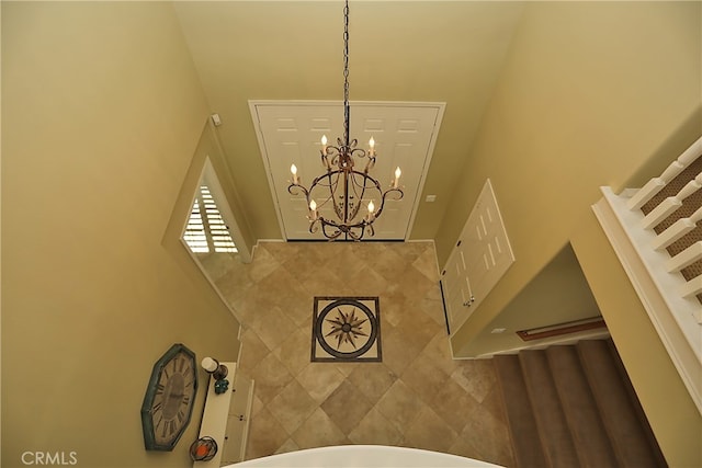 staircase featuring a towering ceiling, a chandelier, and tile walls