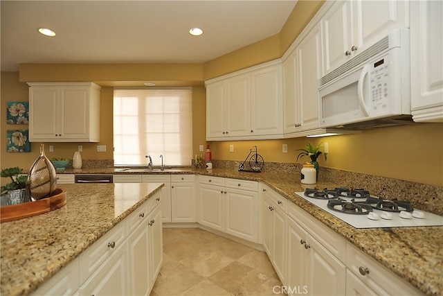 kitchen with white appliances, light stone counters, white cabinetry, and sink