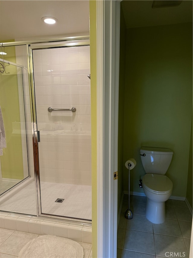 bathroom featuring toilet, tile patterned flooring, and an enclosed shower