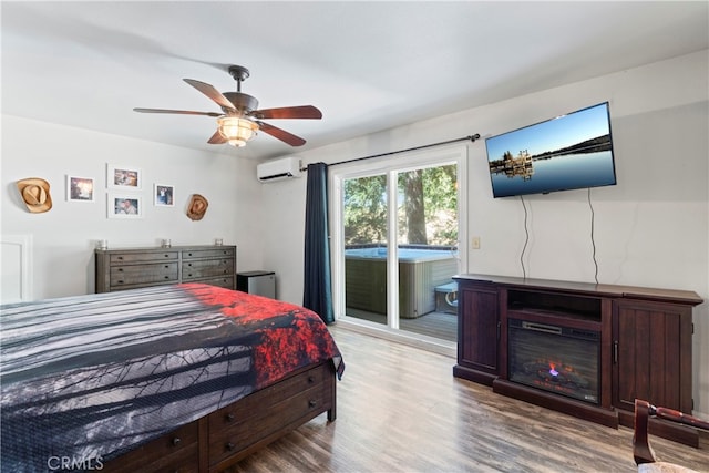 bedroom with hardwood / wood-style flooring, an AC wall unit, ceiling fan, and access to exterior