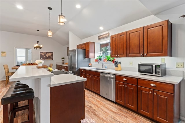 kitchen featuring pendant lighting, a breakfast bar area, lofted ceiling, a kitchen island, and stainless steel appliances