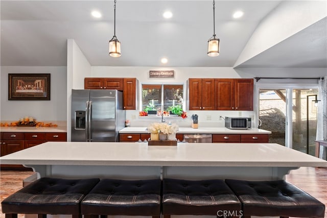 kitchen featuring stainless steel appliances, vaulted ceiling, a kitchen breakfast bar, and a kitchen island